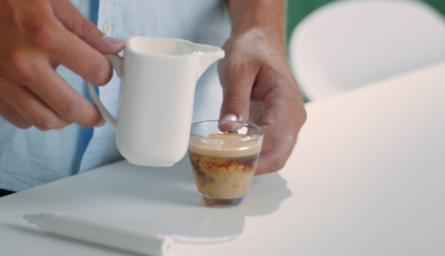 Kleine transparente Kaffeetasse mit einem Schuss Milch