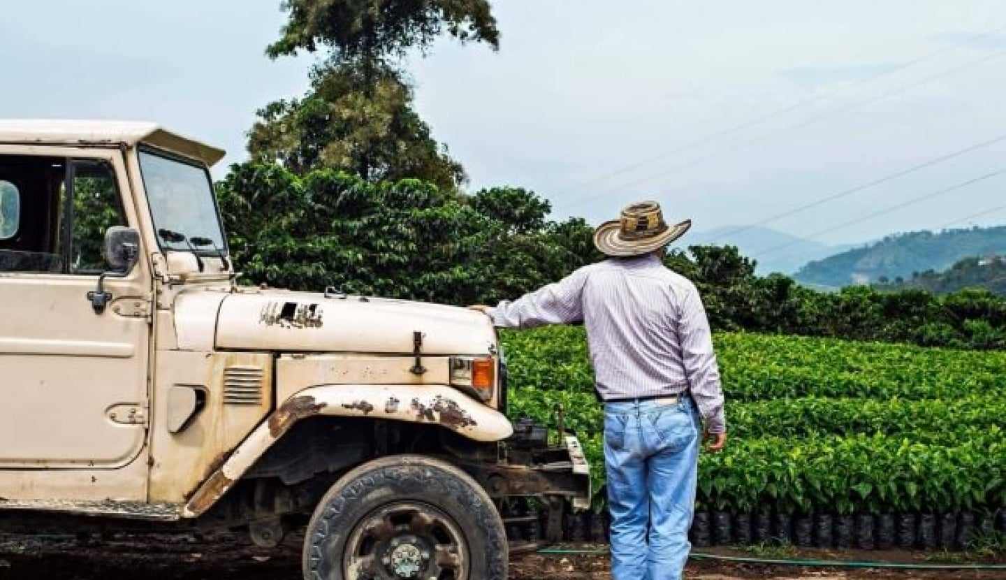 Kaffeebauer an Jeep angelehnt