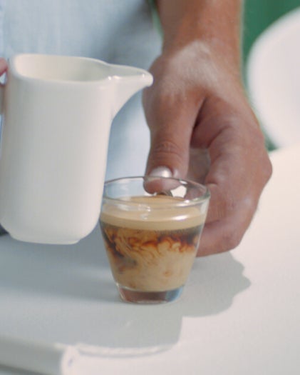 Kleine transparente Kaffeetasse mit einem Schuss Milch