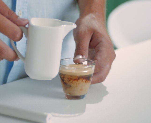 Kleine transparente Kaffeetasse mit einem Schuss Milch