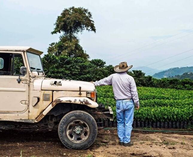 Kaffeebauer an Jeep angelehnt