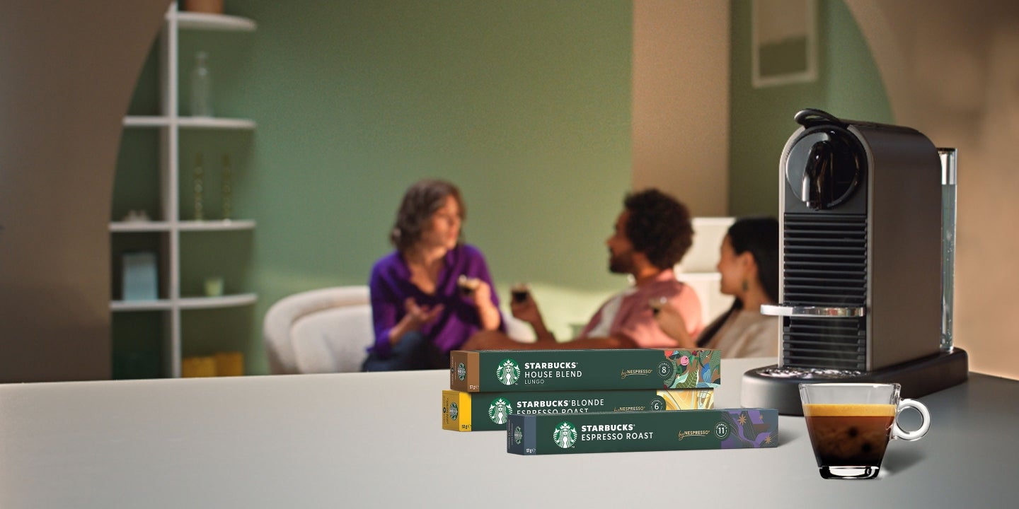 Des amis qui savourent du café, avec en premier plan des emballages de produits Starbucks® by Nespresso® et une machine.