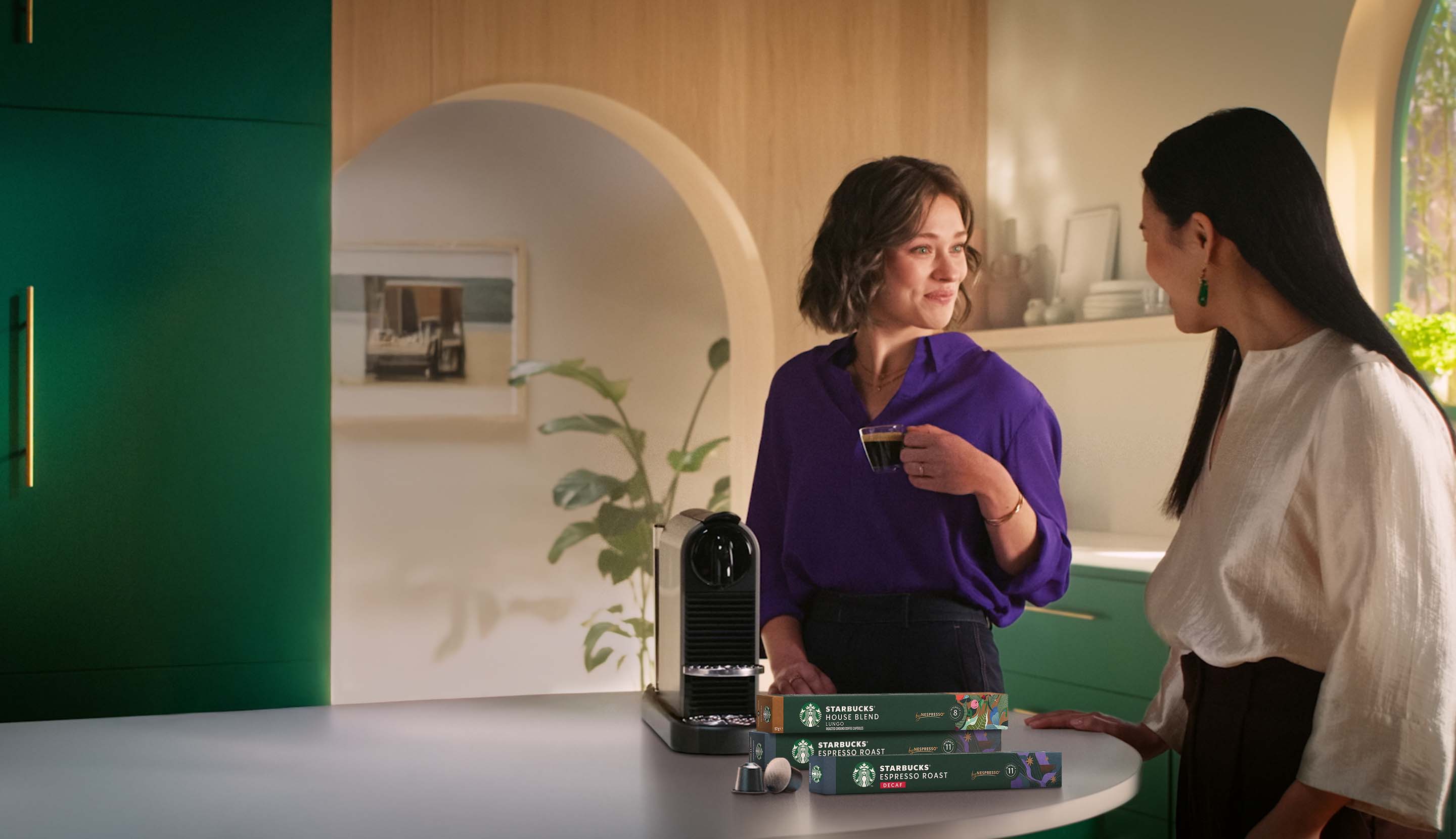 Drei Personen geniessen Kaffee und unterhalten sich. Im Vordergrund stehen eine Nespresso Maschine und mehrere Packungen Star