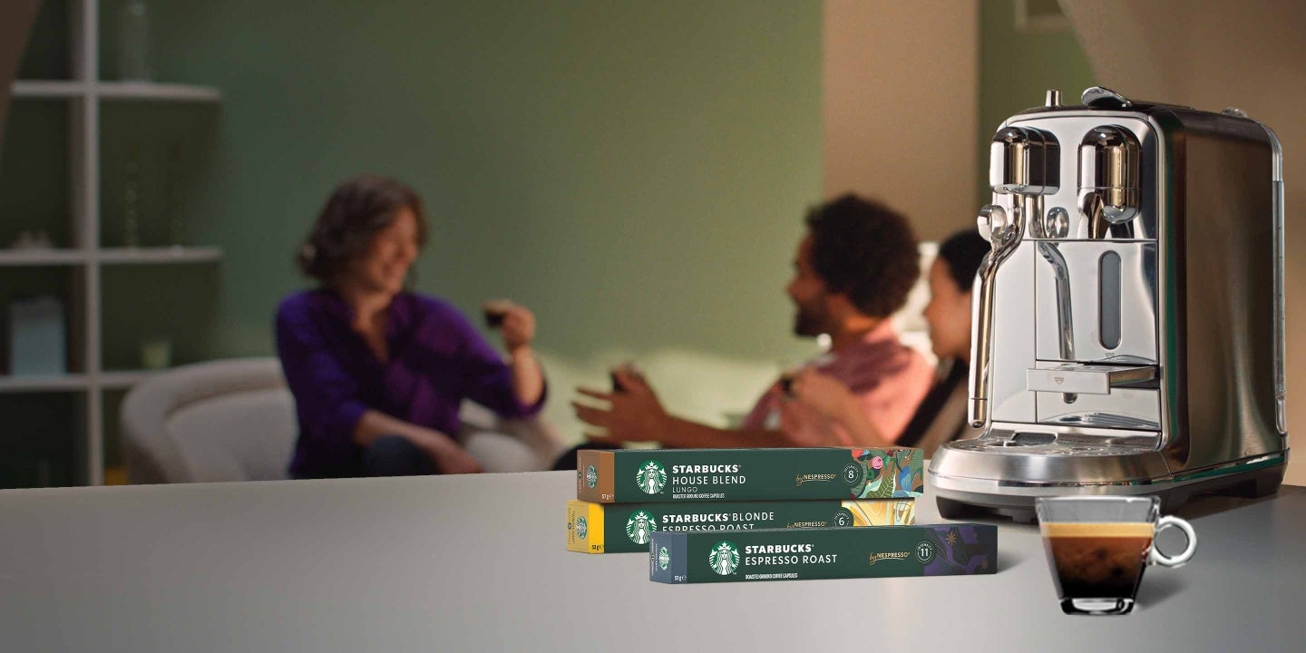 Freunde beim Kaffeetrinken, im Vordergrund sind Starbucks® by Nespresso® Produkte und einen Nespresso®-Maschine zu sehen. 