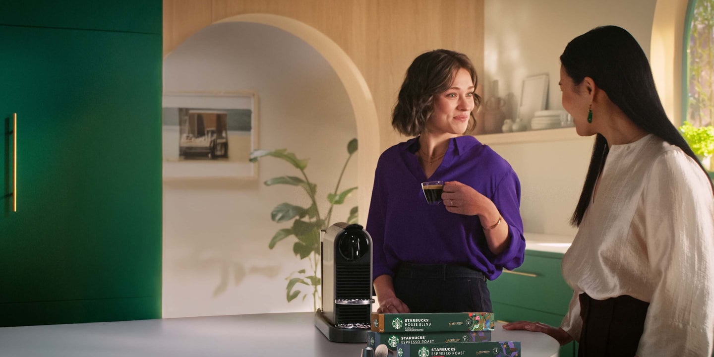 Drei Personen geniessen Kaffee und unterhalten sich. Im Vordergrund stehen eine Nespresso Maschine und mehrere Packungen Star