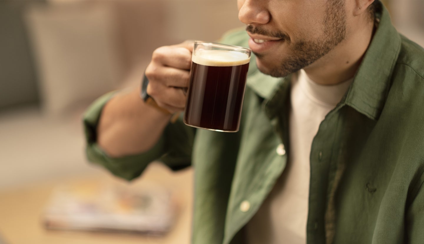 Un café en una taza junto a una máquina de café.