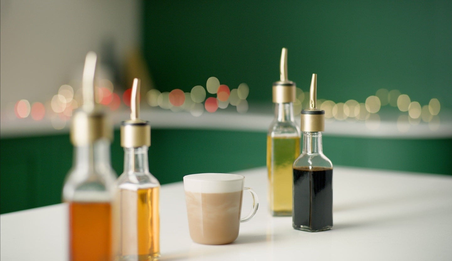 Café sobre una mesa junto a cuatro frascos de sirope