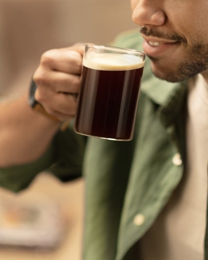 Un café en una taza junto a una máquina de café.