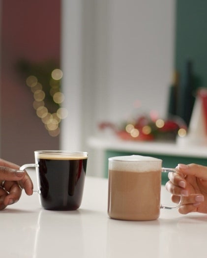 Dos cafés sostenidos por dos manos diferentes