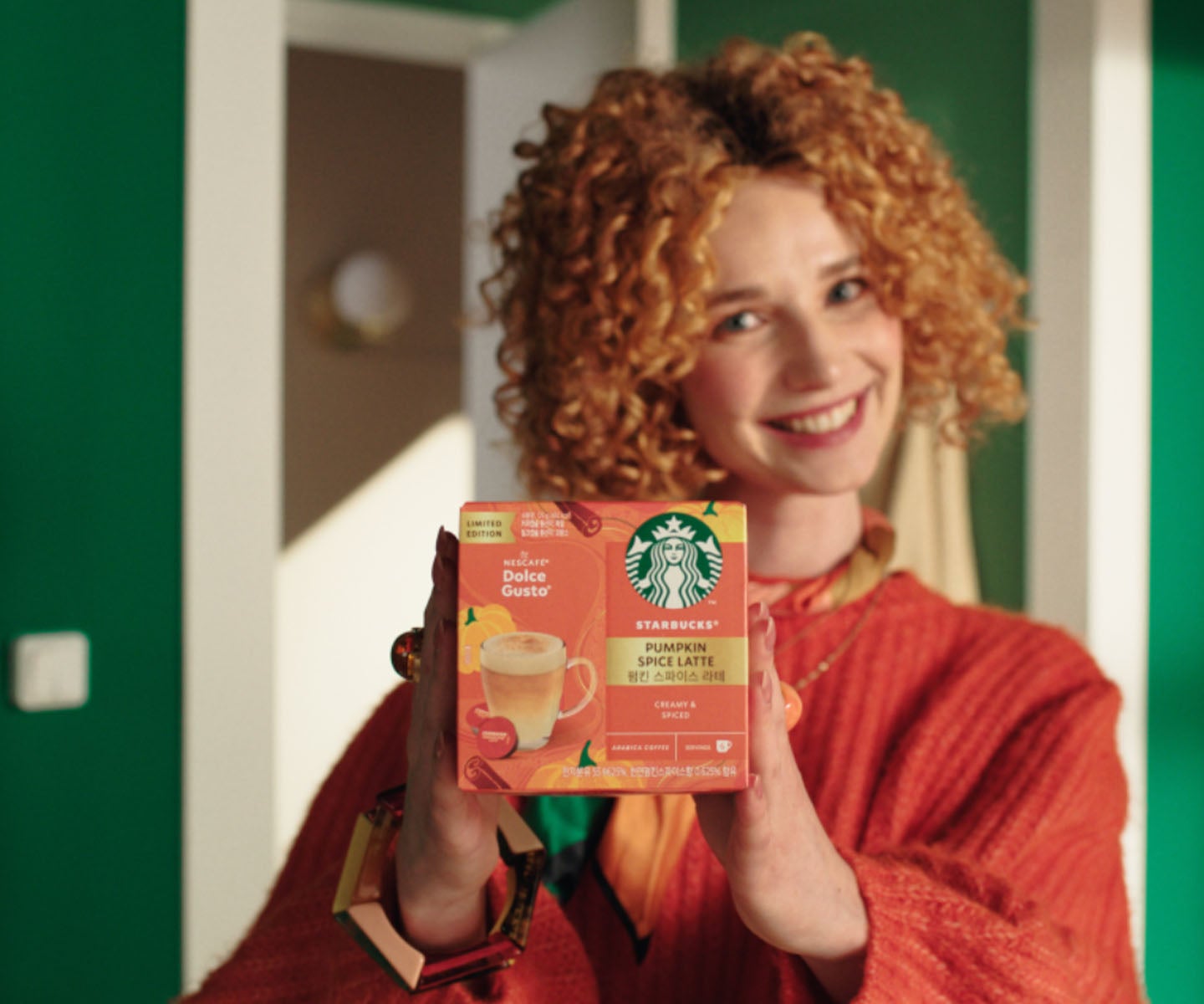 Redhead woman holding up a Starbucks® Pumpkin Spice Latte  package