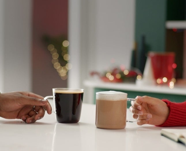 Two coffees being held my two different hands