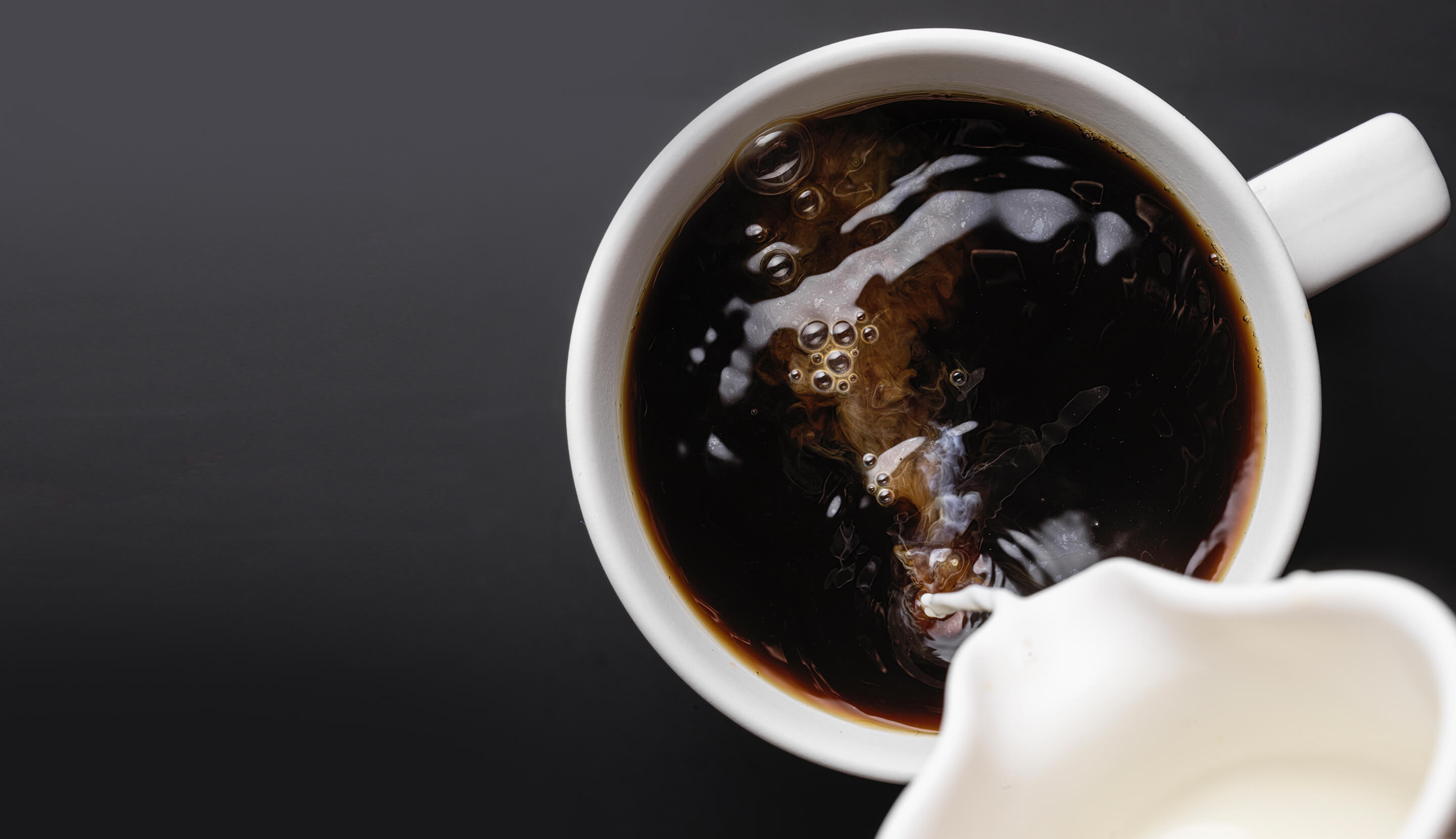 Sipanje mleka u šoljicu crne kafe
