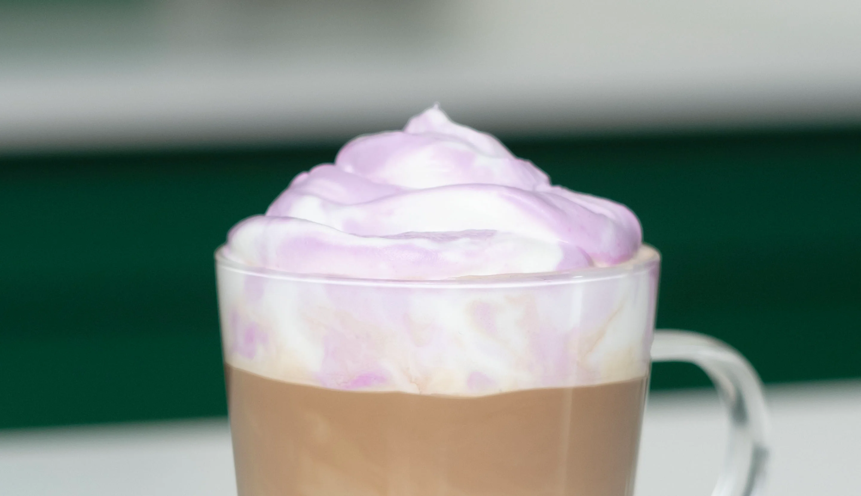 Light lavender whipped cream spooned onto a layered coffee, creating a rustic homemade finish.