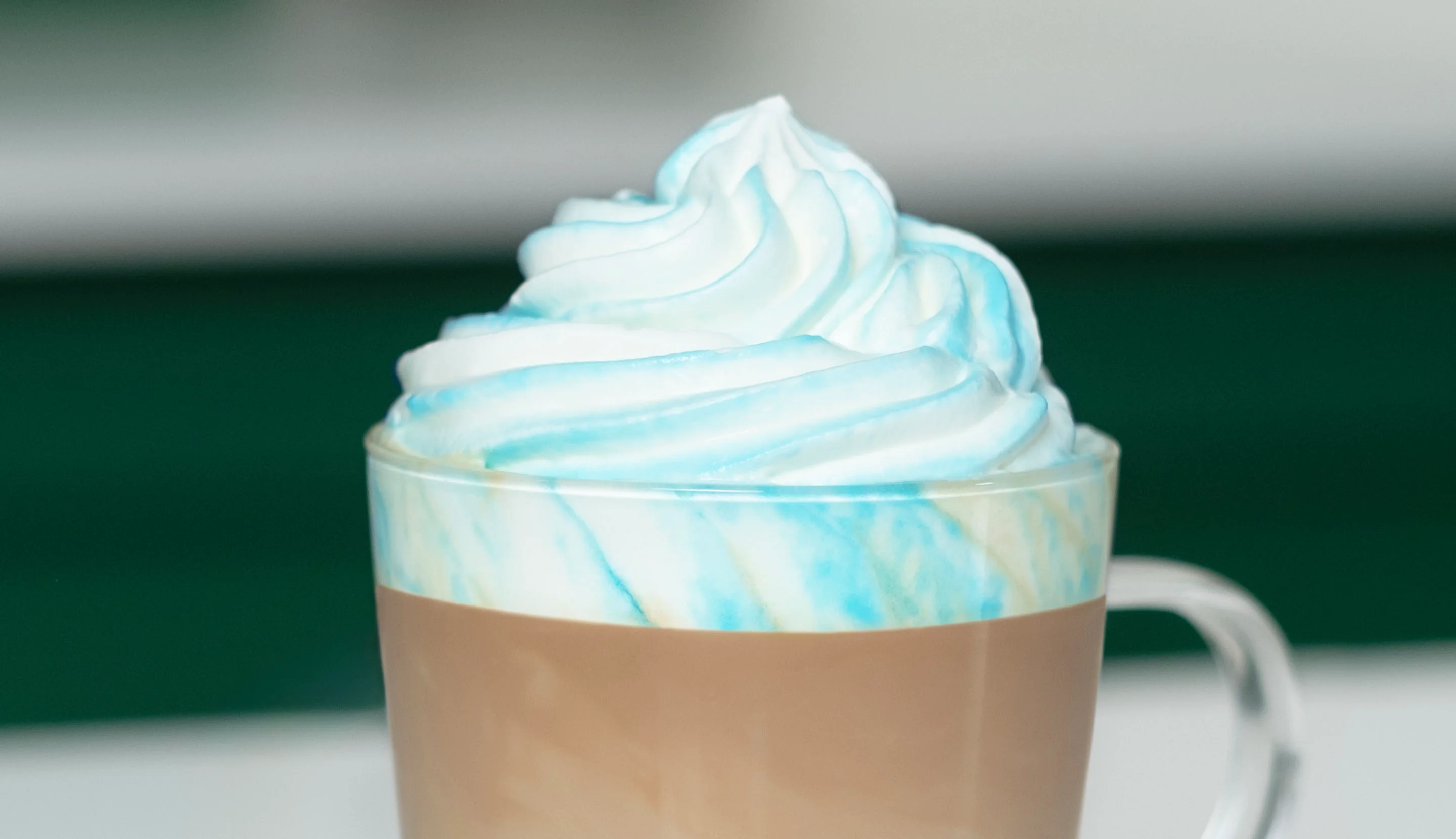 Blue whipped cream tops a layered coffee, creating a colourful ombre effect.