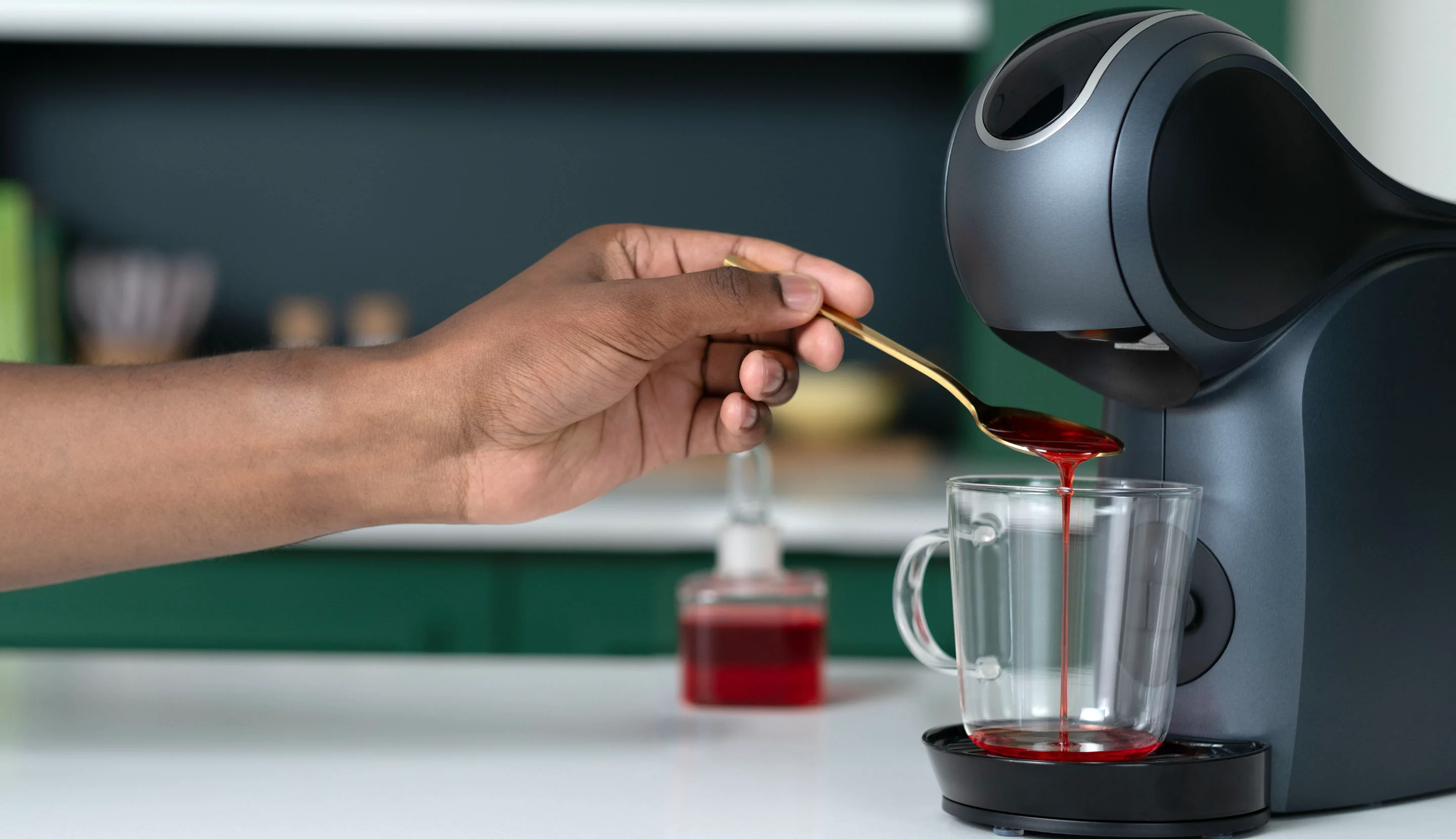 Adding red syrup to a mug before brewing coffee for a colourful layered drink.