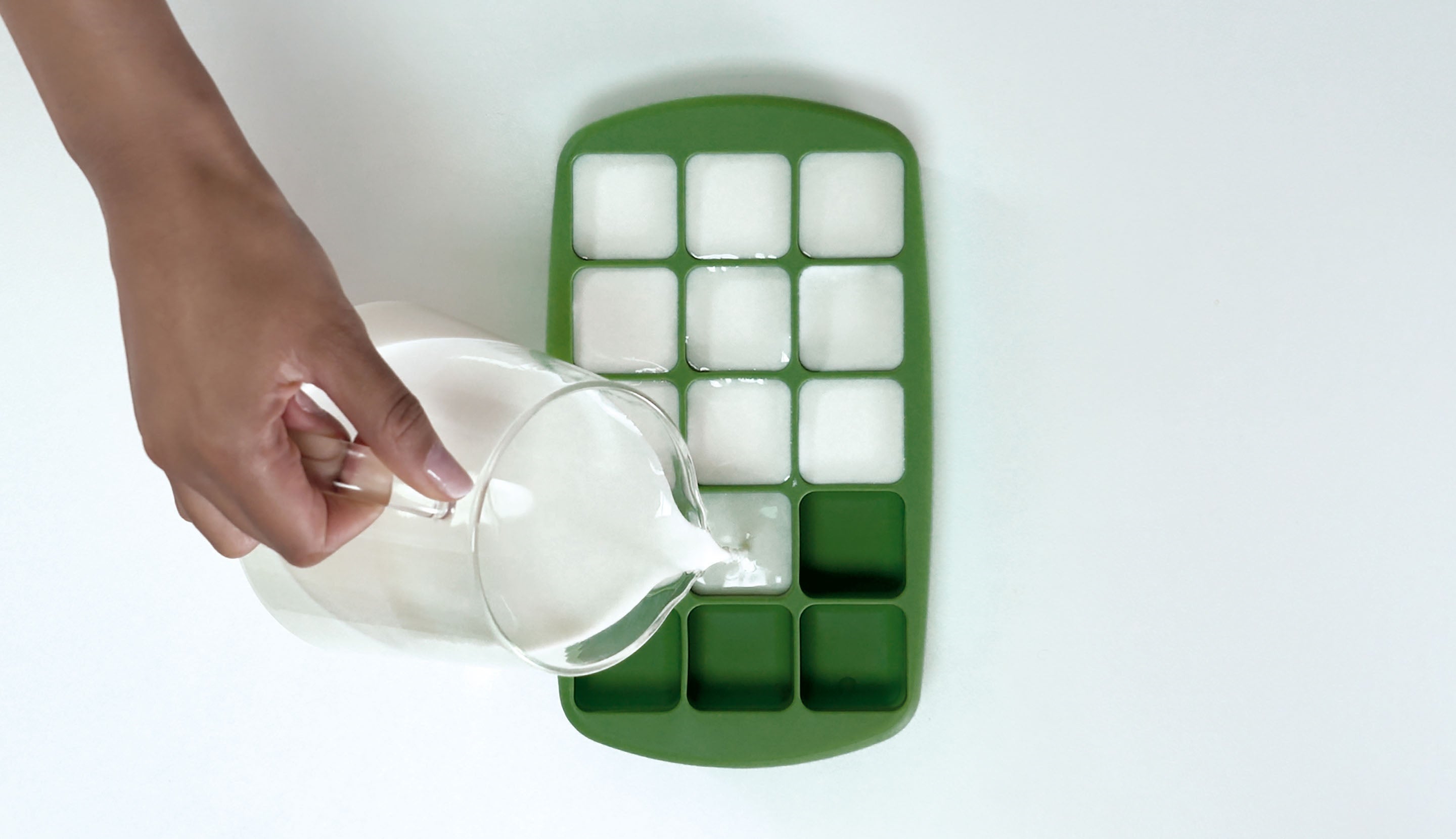 Pouring milk into an ice cube tray for iced Starbucks® coffee.