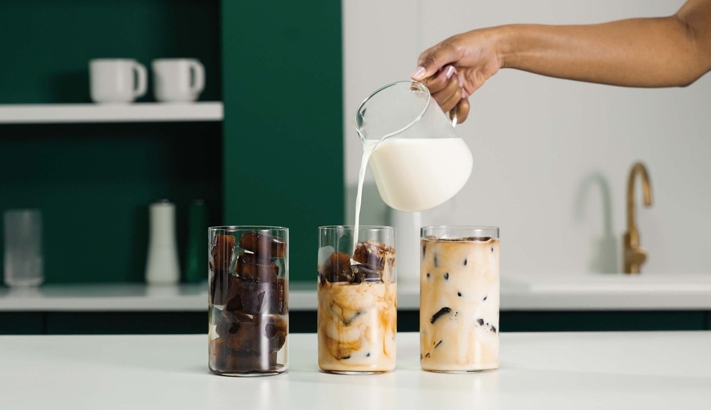 Pouring milk over coffee ice cubes to make an iced Starbucks® coffee.