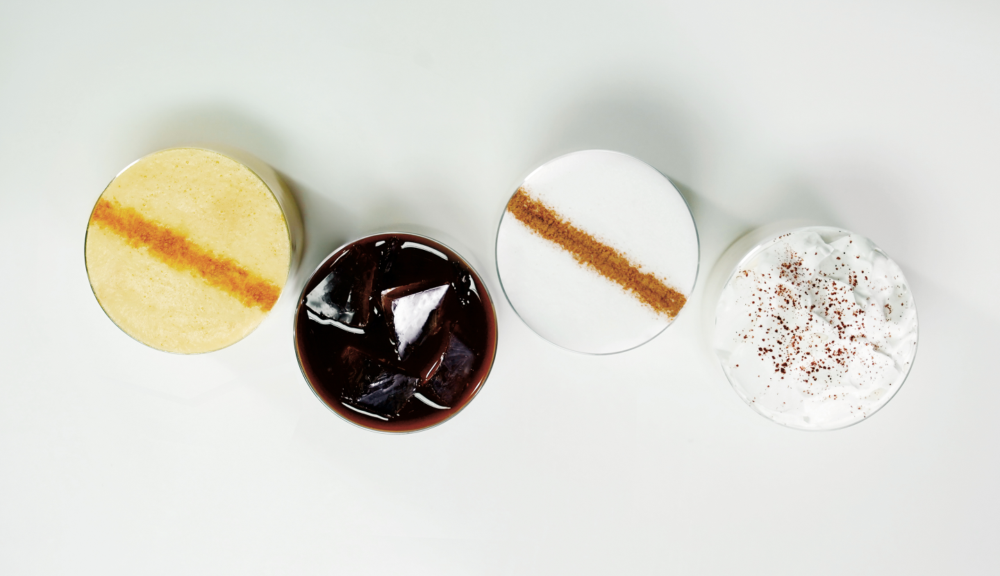 Overhead view of icedStarbucks® coffees topped with cinnamon, cocoa and whipped cream.