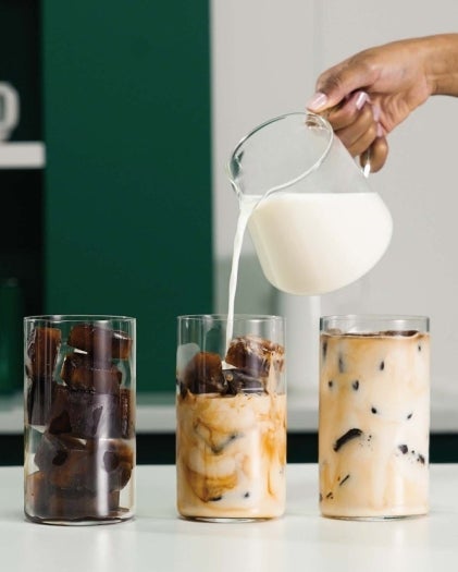 Pouring milk over coffee ice cubes to make an iced Starbucks® coffee.