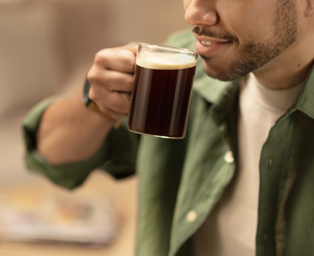 A coffee in a cup standing next to a coffee machine