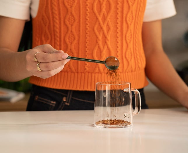 Person making soluble coffee in a glass