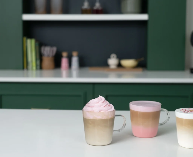 Three colourful layered coffee drinks with pink foam and sprinkles, inspiring creative coffee customisation.